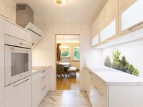 Moderne, helle Küche mit weißen Hochglanzfronten, Spülmaschine, Küchenzeille und Hängeschränke.