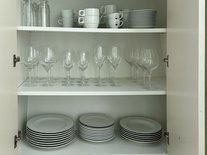 Voll ausgestatteter Küchenschrank der Suite Nachtigall mit Gläsern, Tassen und Tellern