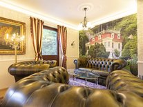 Stilvoll eingerichtetes Wohnzimmer mit Leder-Sitzgarnitur und dekorativem Wandbild.