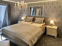 Doppelbett im zweiten Schlafzimmer der Suite Nachtigall mit grauer Tapete und Nachttischen