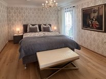 Schlafzimmer der Suite Romantik mit Gemälde, Kronleuchter und stilvoller Einrichtung