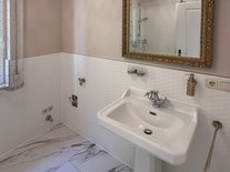 Badezimmer der Suite Romantik mit klassischem Waschbecken und großem goldgerahmten Spiegel.