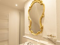 Badezimmer der Suite Nachtigall mit goldenem Spiegel und Waschbecken