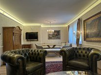 Wohnzimmer der Suite Romantik mit Chesterfield-Sesseln, Essbereich und Kronleuchtern