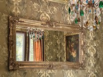 Prunkvoller Spiegel im Turmzimmer Louise der Suite Nachtigall mit Blick auf Gemälde und Kronleuchter