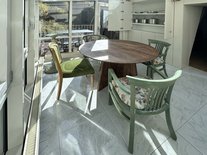 Heller Wintergarten der Suite Nachtigall im Schlössle Seeburg mit rundem Holztisch, grünen Stühlen und Zugang zur Terrasse.