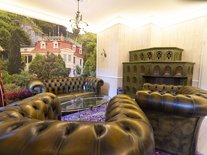 Stilvoll eingerichtetes Wohnzimmer mit Leder-Sitzgarnitur, historischem Kachelofen und dekorativem Wandbild.