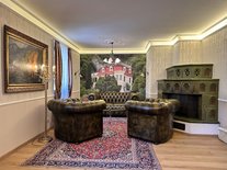 Wohnzimmer der Suite Romantik mit grünem Kachelofen und Chesterfield-Sofas