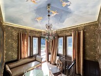 Suite Nachtigall – Turmzimmer Luise mit Engels-Deckenmalerei, Kristallleuchter und Sofa im Schlossstil.