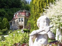 Schlössle Seeburg mit Blick auf den Garten und eine dekorative Steinfigur im Vordergrund