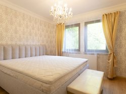 Helles Schlafzimmer mit großem Bett (King size), stilvoller Tapete und Kronleuchter – ideal für erholsamen Schlaf mit Blick ins Grüne.