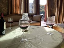 Gemütliche Stimmung im Turmzimmer Luise der Suite Nachtigall mit Rotwein und Kristallgläsern auf gedecktem Tisch.